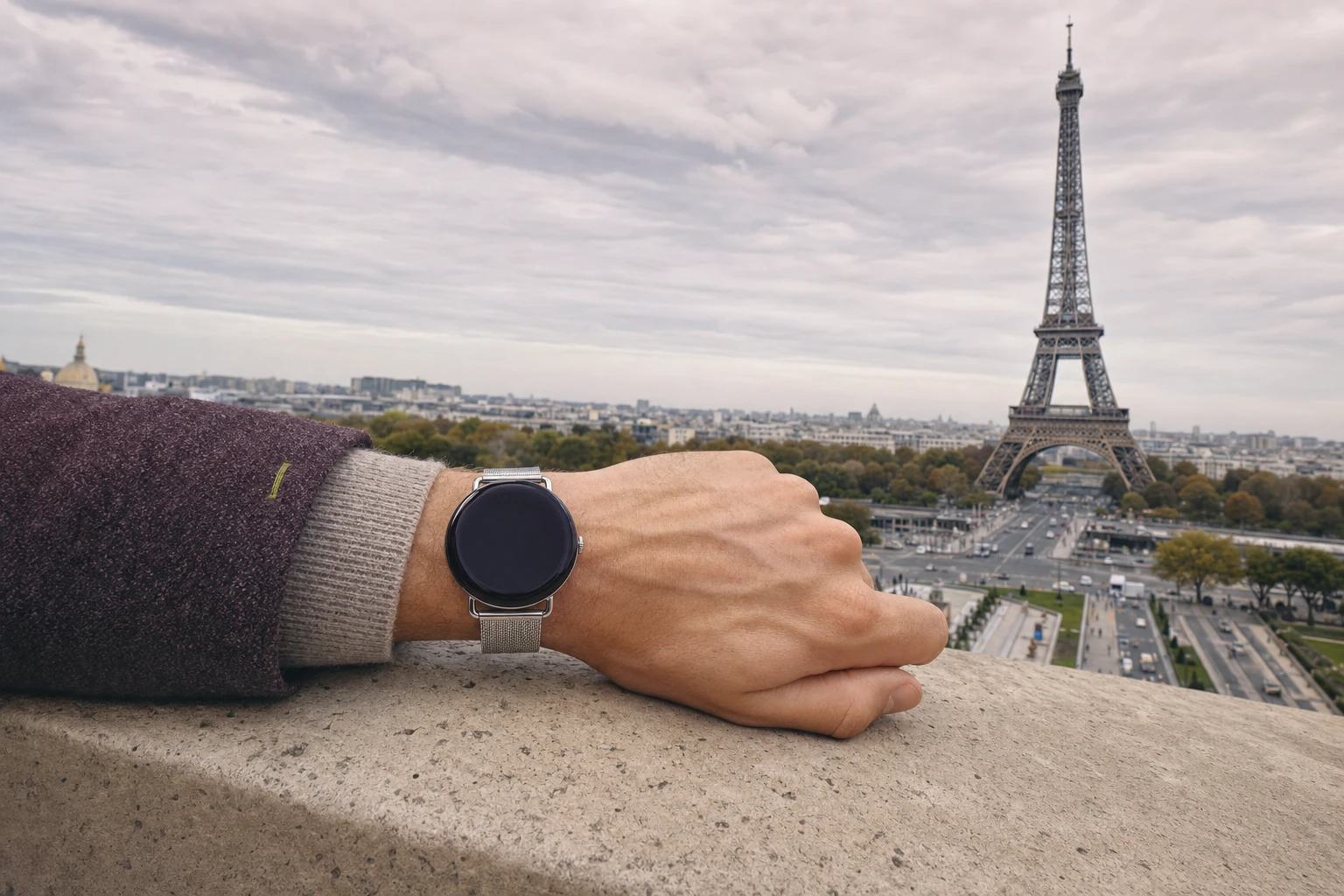 A traveler rests a wrist on a Trocadéro terrace with the Eiffel Tower and Roam O'Clock watch both visible
